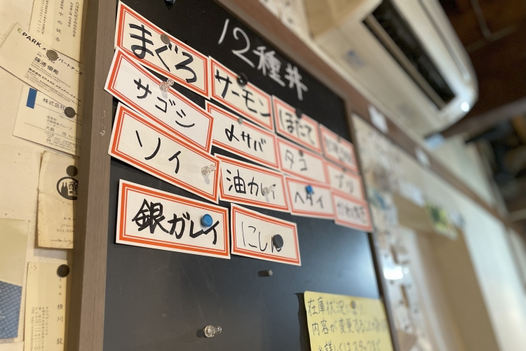 お店名物の丼ぶりに乗る魚が書いてある黒板