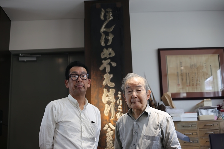 20代目の目細勇治さんと19代目の目細伸一さん。年代物の看板を今も大切に飾っている